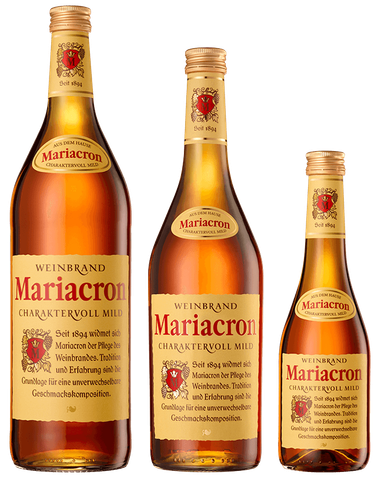 Drei Flaschen Mariacron Weinbrand in verschiedenen Größen stehen nebeneinander, jede mit einem goldenen Etikett und rotem Wappen.