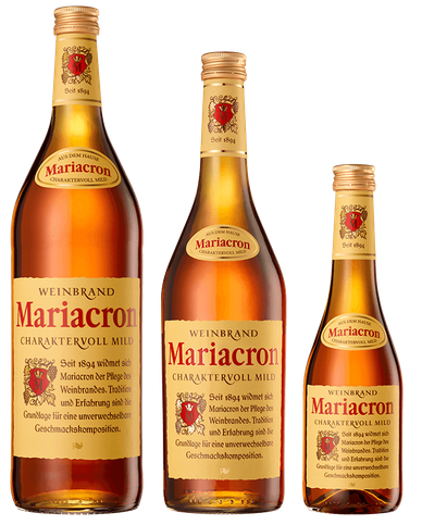 Drei Flaschen Mariacron Weinbrand in verschiedenen Größen stehen nebeneinander, jede mit einem goldenen Etikett und rotem Wappen.
